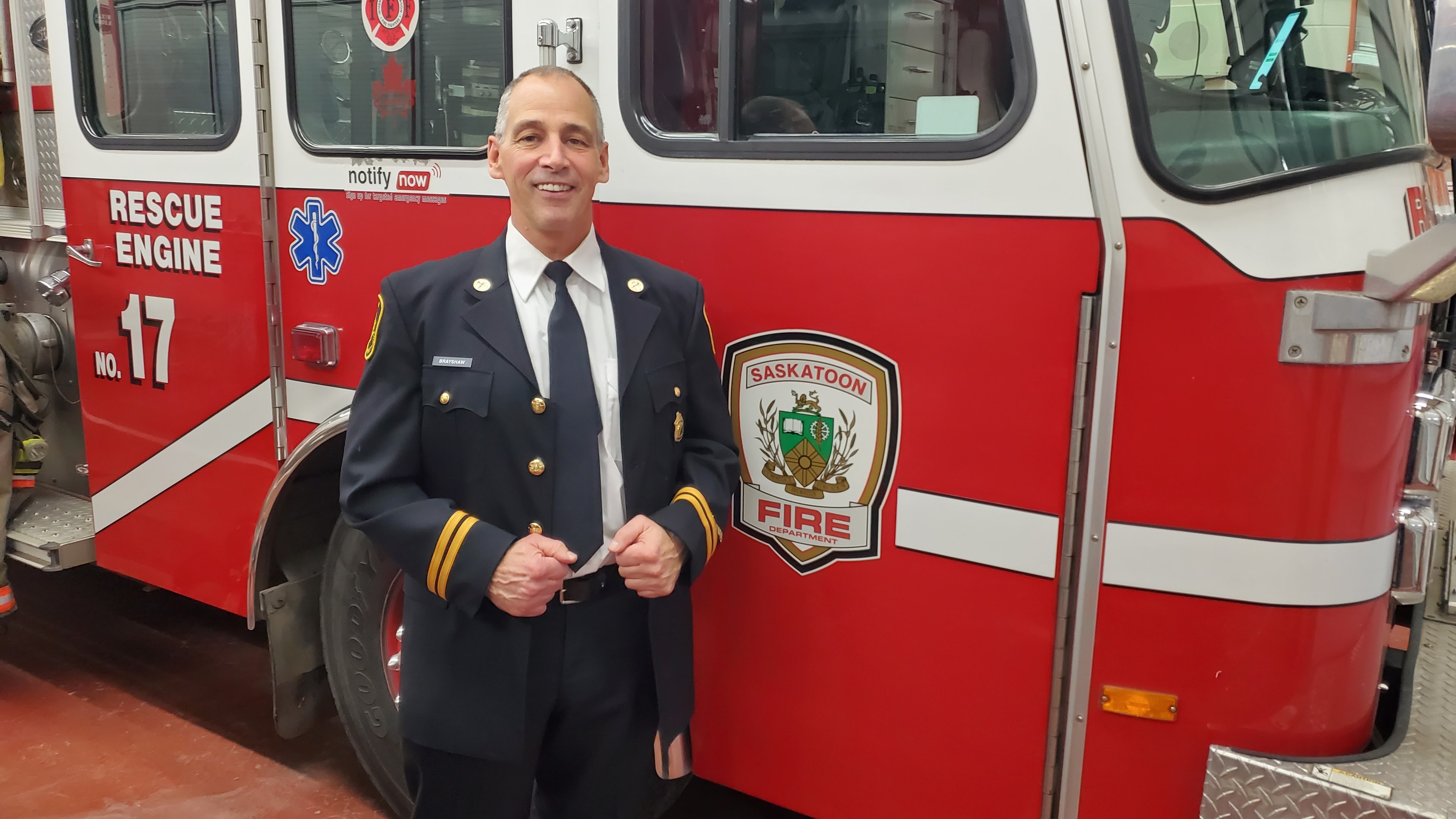Jim Brayshaw in dress uniform beside a Saskatoon Fire Department rescue engine